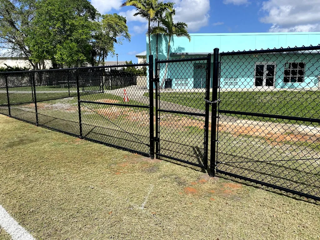 Black chain link fence with barbed wire at baseball field