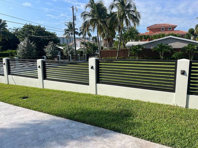 Black welded aluminum slat fence on a white wall with columns