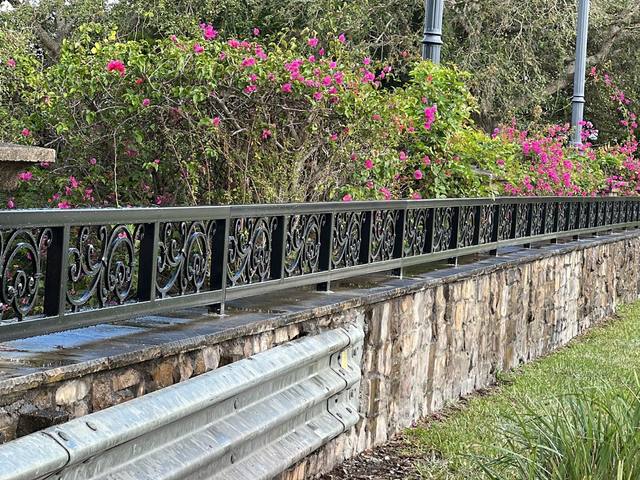 Decorative black metal railing along a stone wall