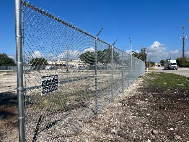 Galvanized chain link security fence with barbed wire along a commercial lot