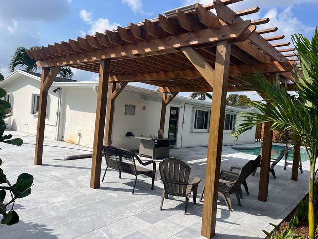 Stained wood pergola over a paved patio beside a pool
