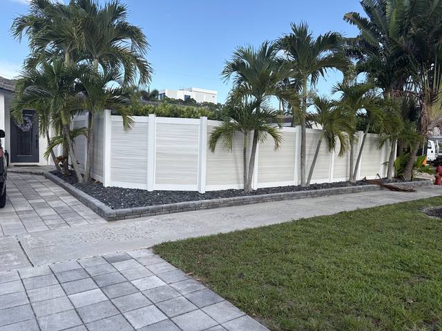 White PVC privacy fence behind a row of palms