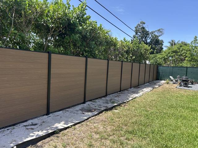 Composite fence panels in black posts along a lawn