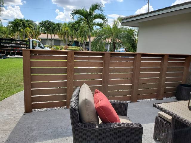 Stained horizontal wood privacy screen beside patio seating